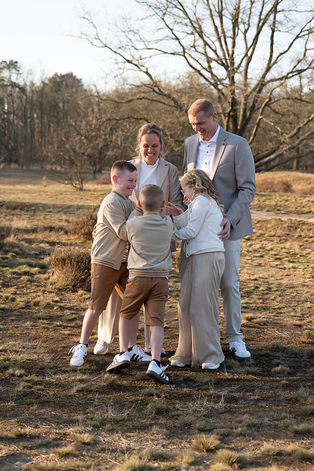 familiefoto van een gezin met 3 kinderen op de heide tijdens het gouden uurtje