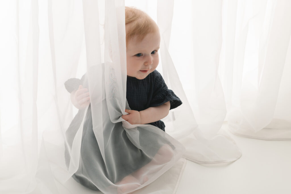 baby die zich verstopt achter gordijn en komt piepen