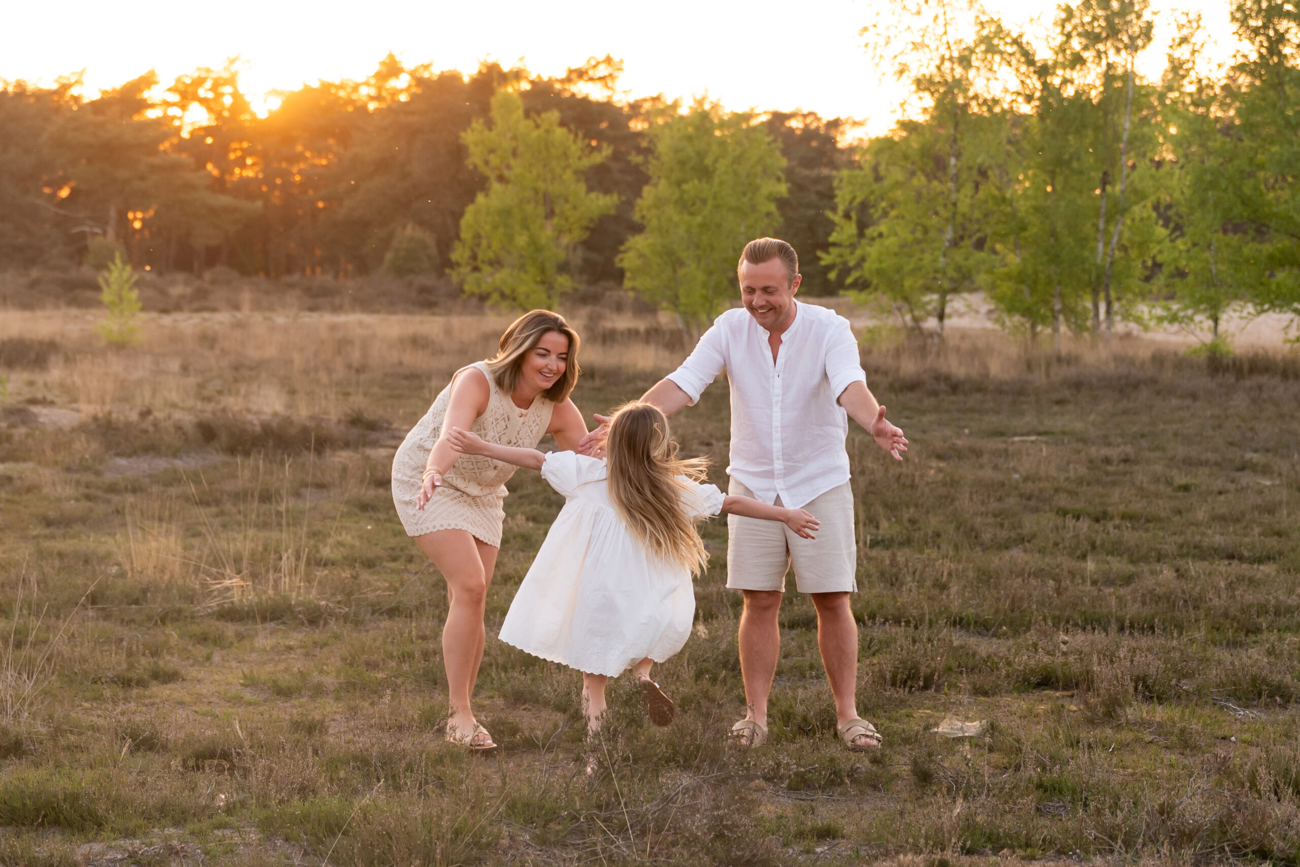 mama ene papa die samen met hun dochtertje plezier hebben tijdens Golden Hour op de heide in Kalmthout