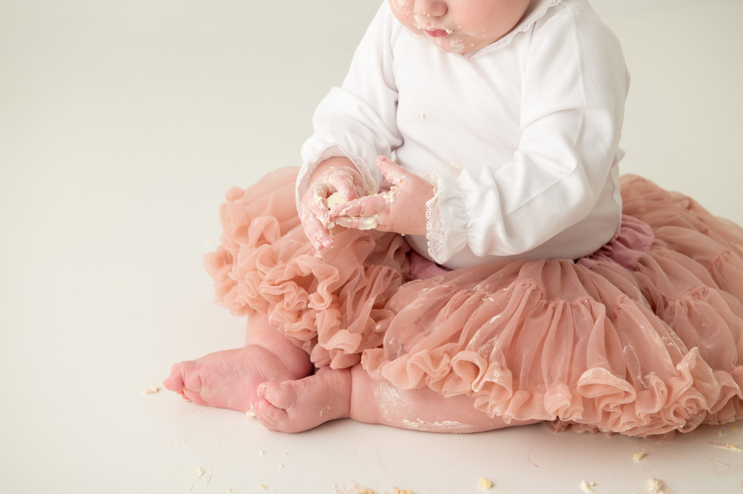 Close-up van kleine handjes en voetjes van een baby die een taart ontdekken en gezicht kind(jes) in sociale media