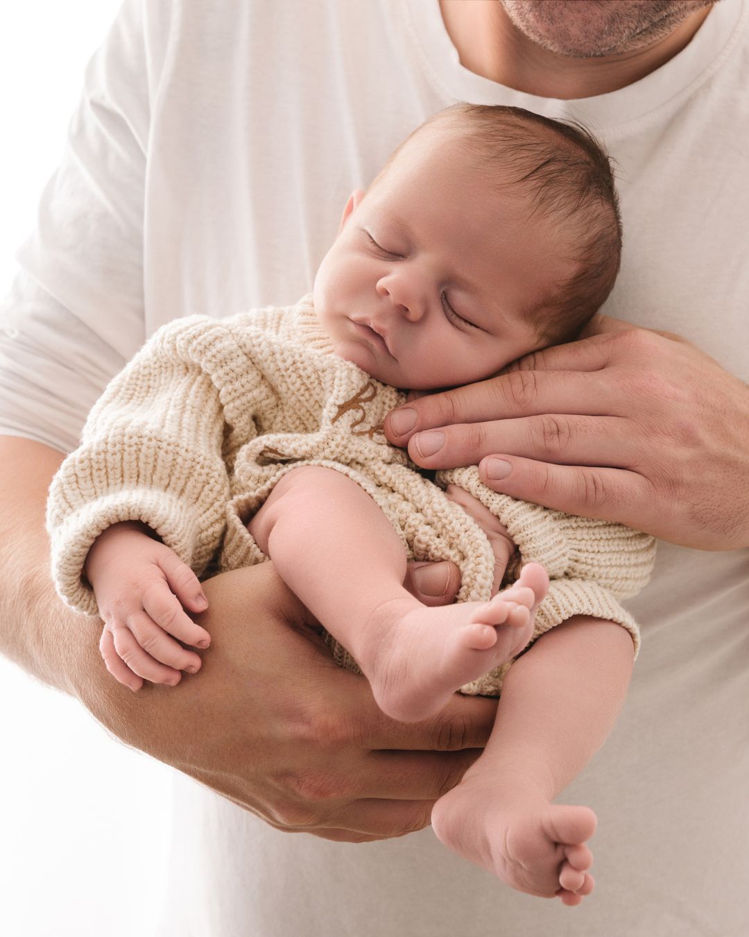 pasgeboren baby veilig in de handen van papa